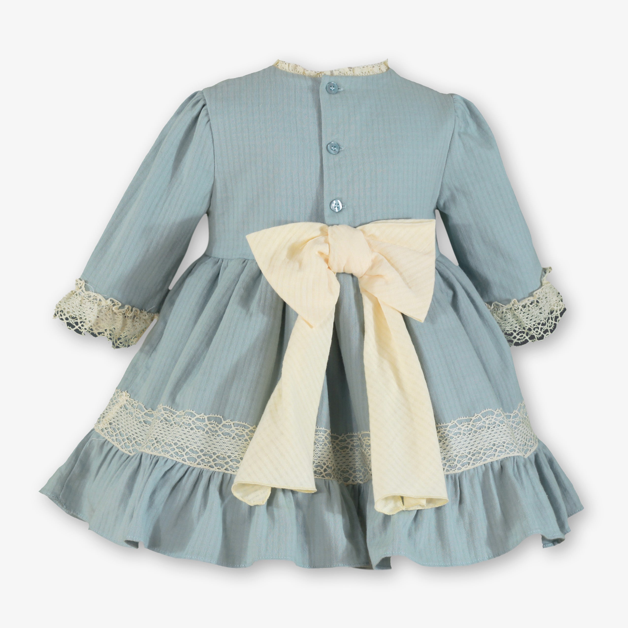 Vista trasera con gran lazada marfil y botonadura del vestido azul verdoso para niña firma Miranda