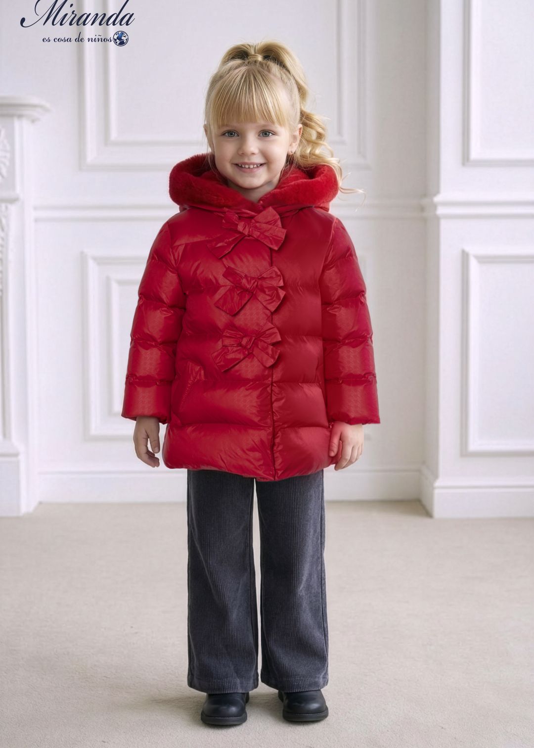 Niña sonriente luciendo el abrigo parka rojo de invierno con capucha de pelo de la marca española Miranda