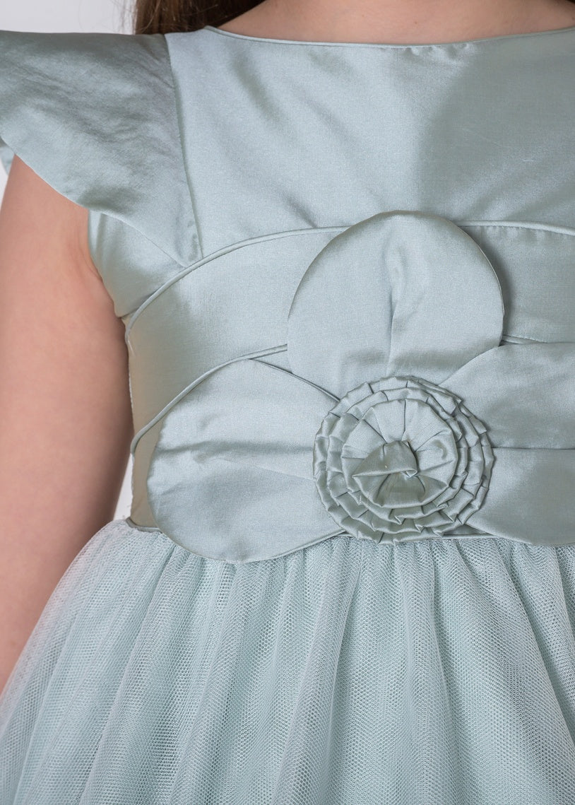 Primer plano de la flor artesanal y tejido satinado del vestido de ceremonia Caeli.