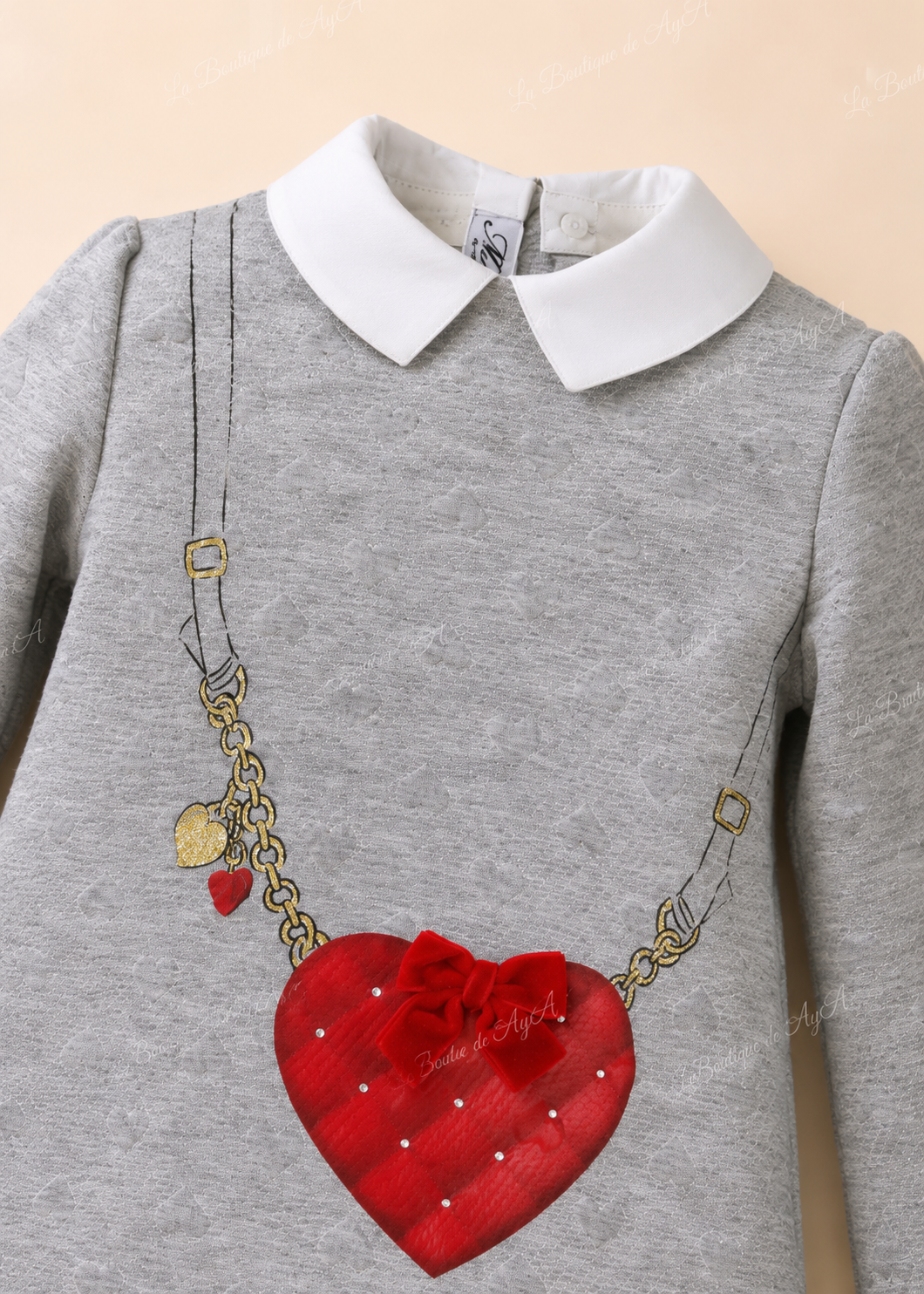Detalle del cuello blanco y corazón rojo con lazo del vestido Miranda