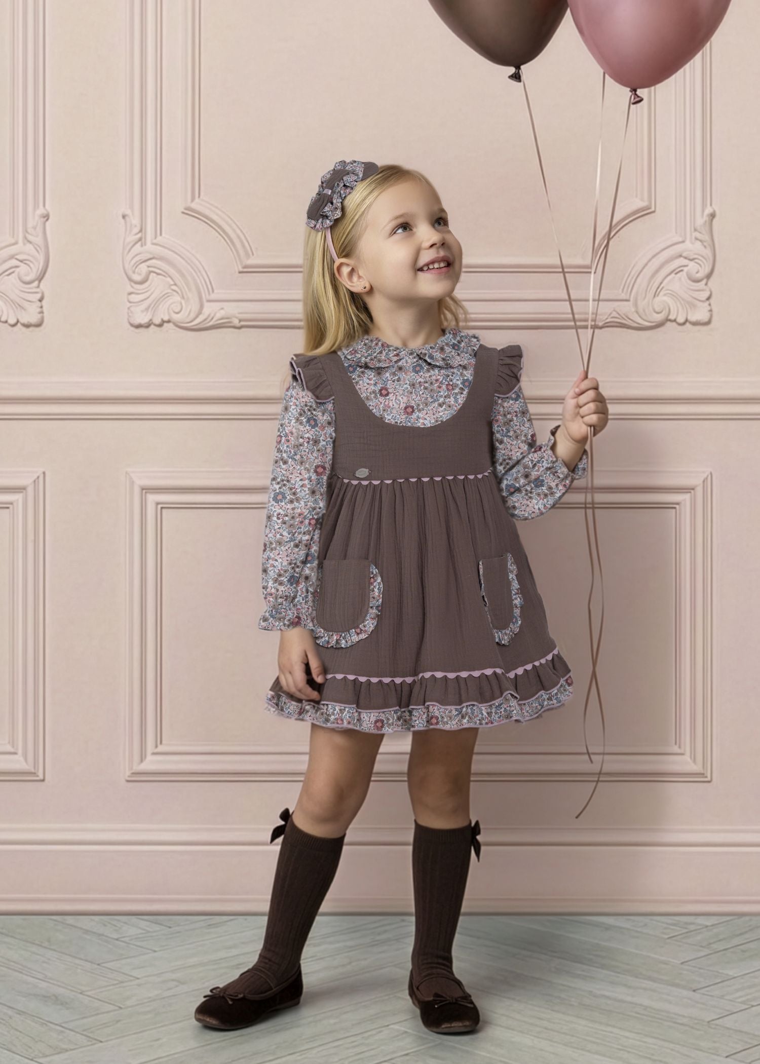 Niña luciendo el vestido efecto pichi marrón con blusa de flores de la marca española Miranda