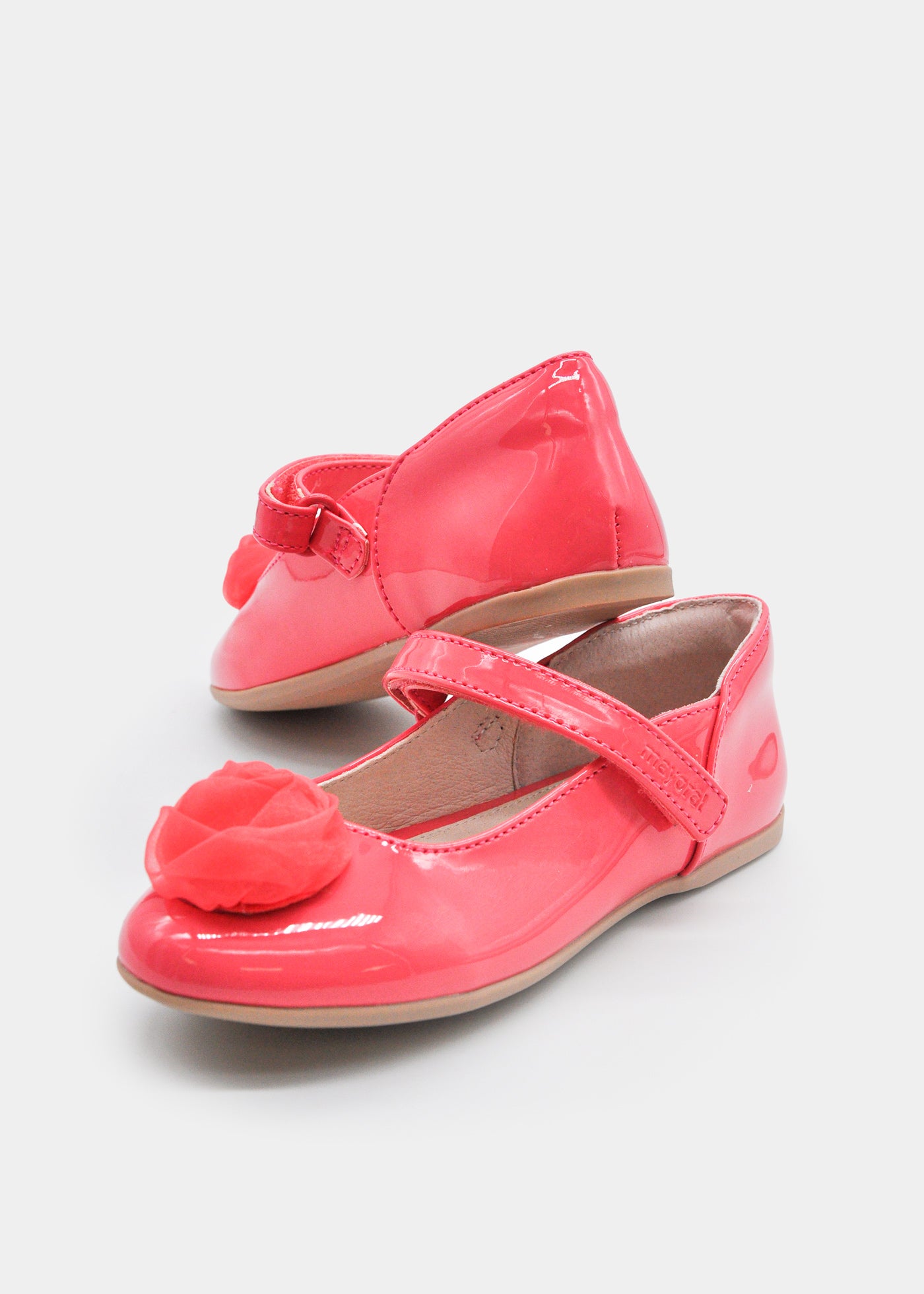 Zapato tipo mercedita de niña Mayoral en color coral brillante (charol) con detalle de flor de tela y cierre de velcro.