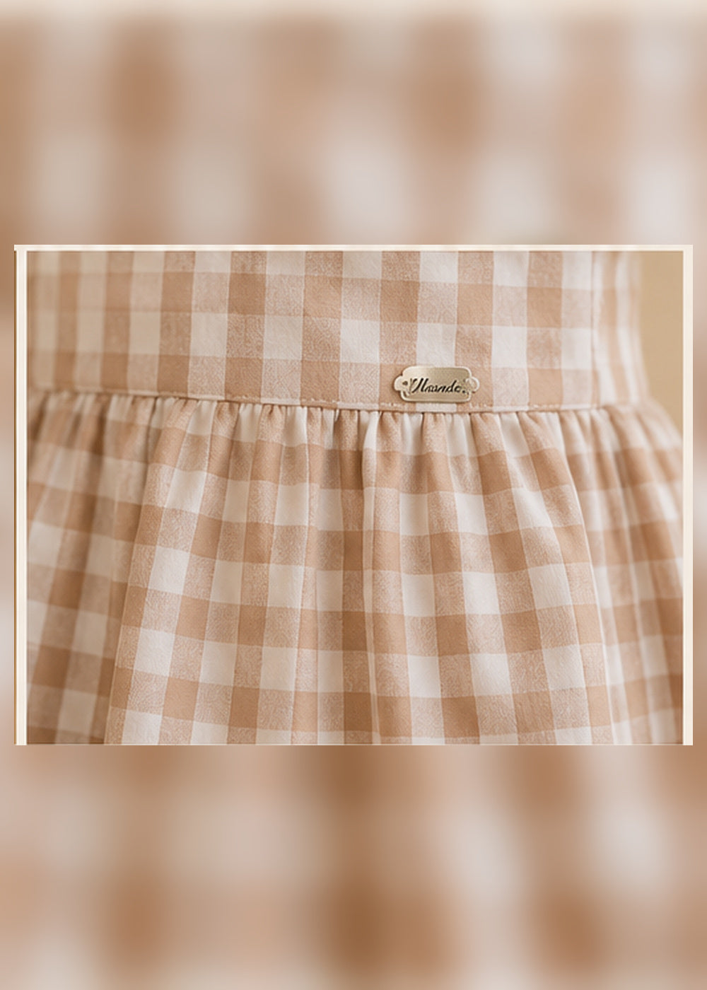 Detalle del tejido de cuadros beige y placa Miranda del vestido infantil
